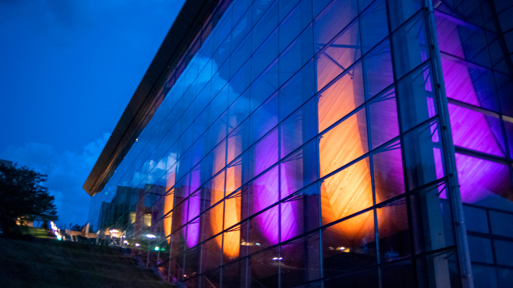 The EMPAC exterior lit from within with purple and gold at night. 