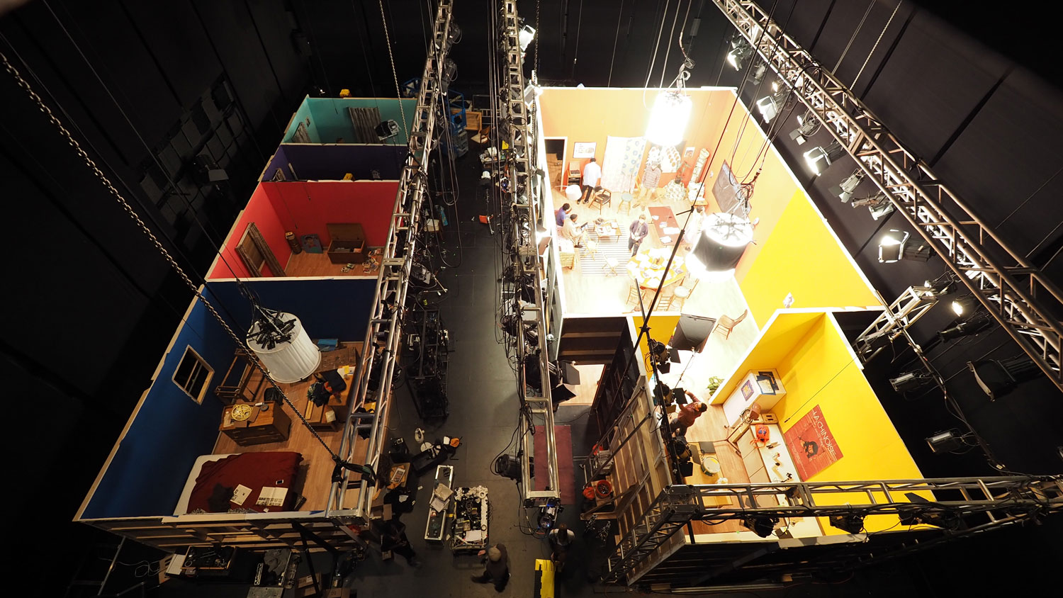 An aerial view of an entire film set of colorful rooms built in black box theater. 