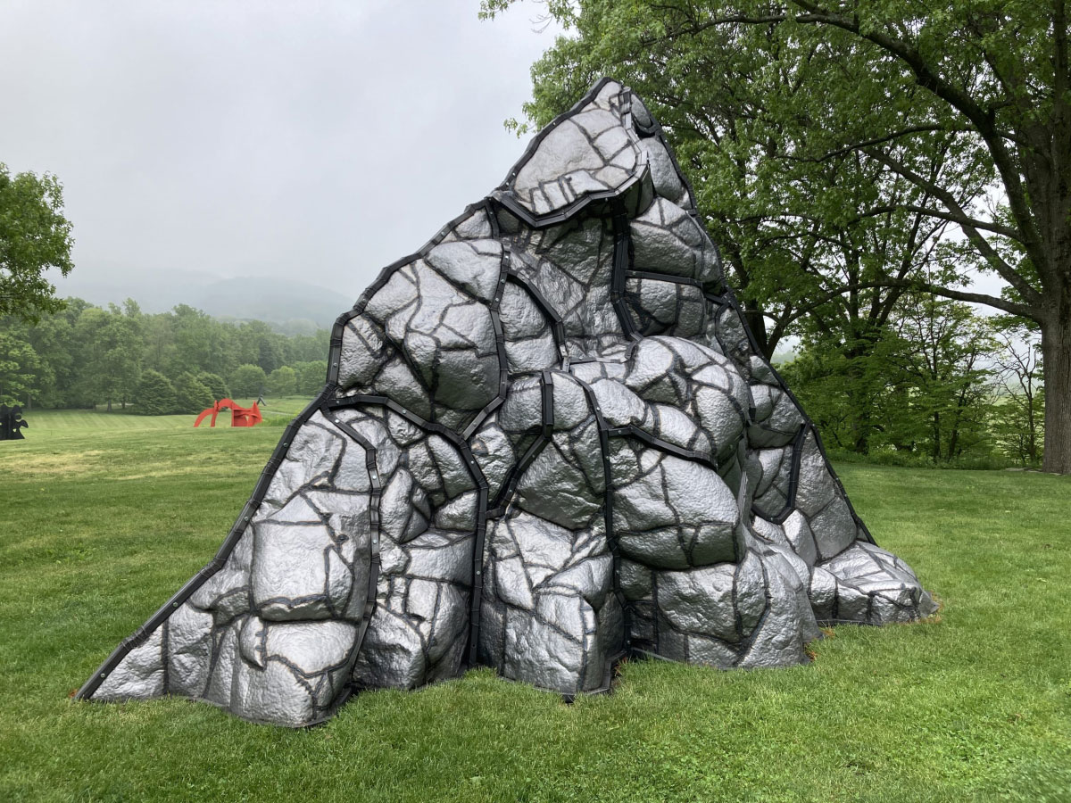 a sculpture of a volcano sitting in the rolling green grass at storm king art center in the hudson valley, ny