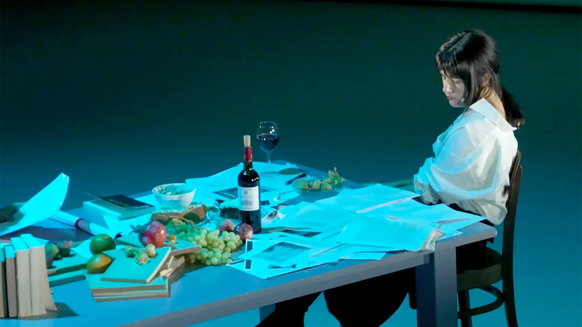 a woman sitting at a table covered in papers 