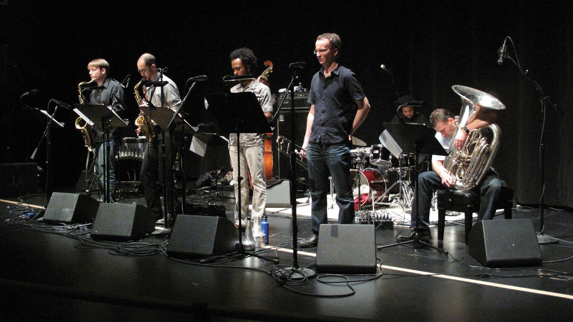 A small group of musicians playing a concert on a black stage. 