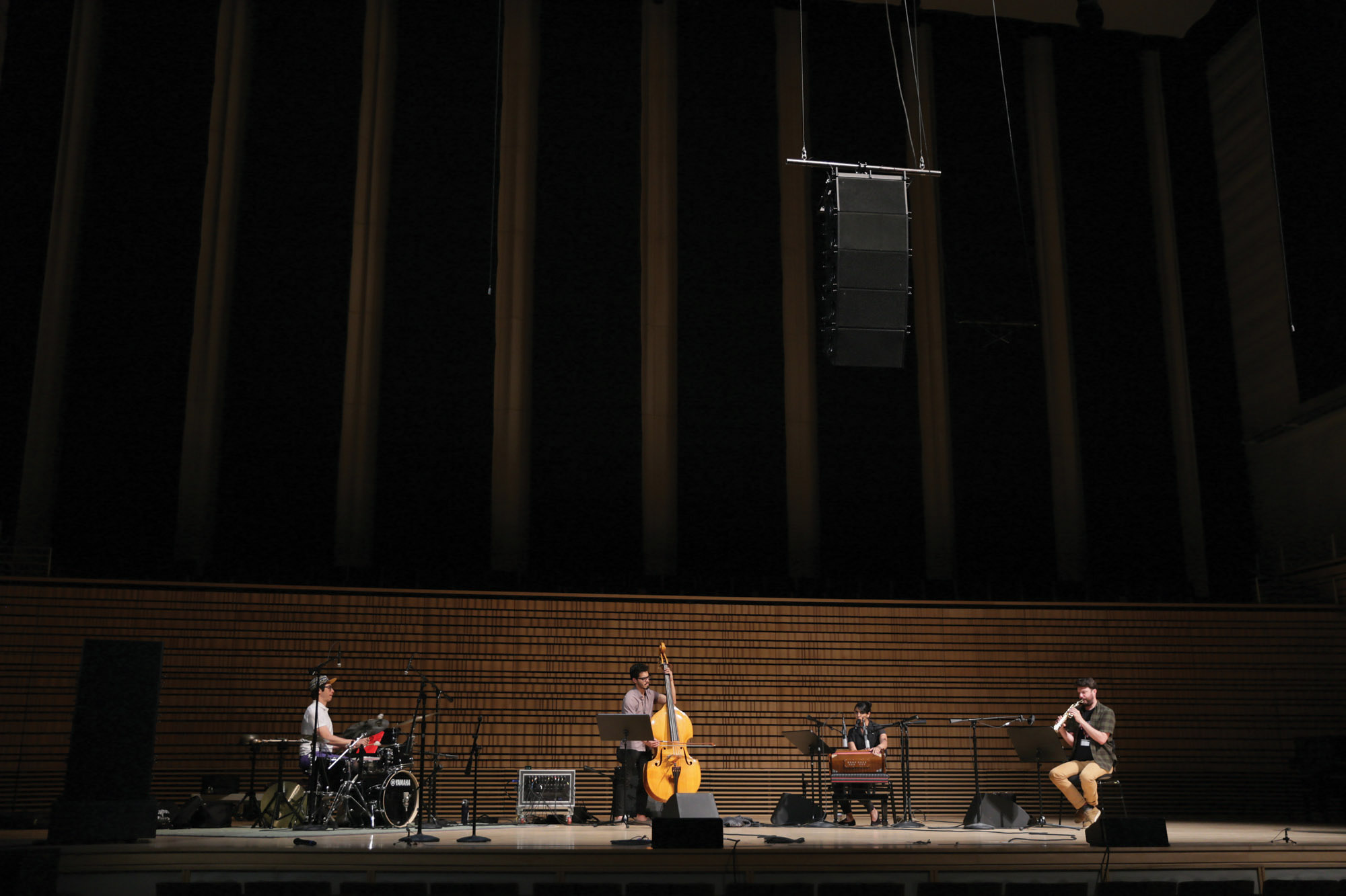 A quartet playing spread out across the concert hall stage. 