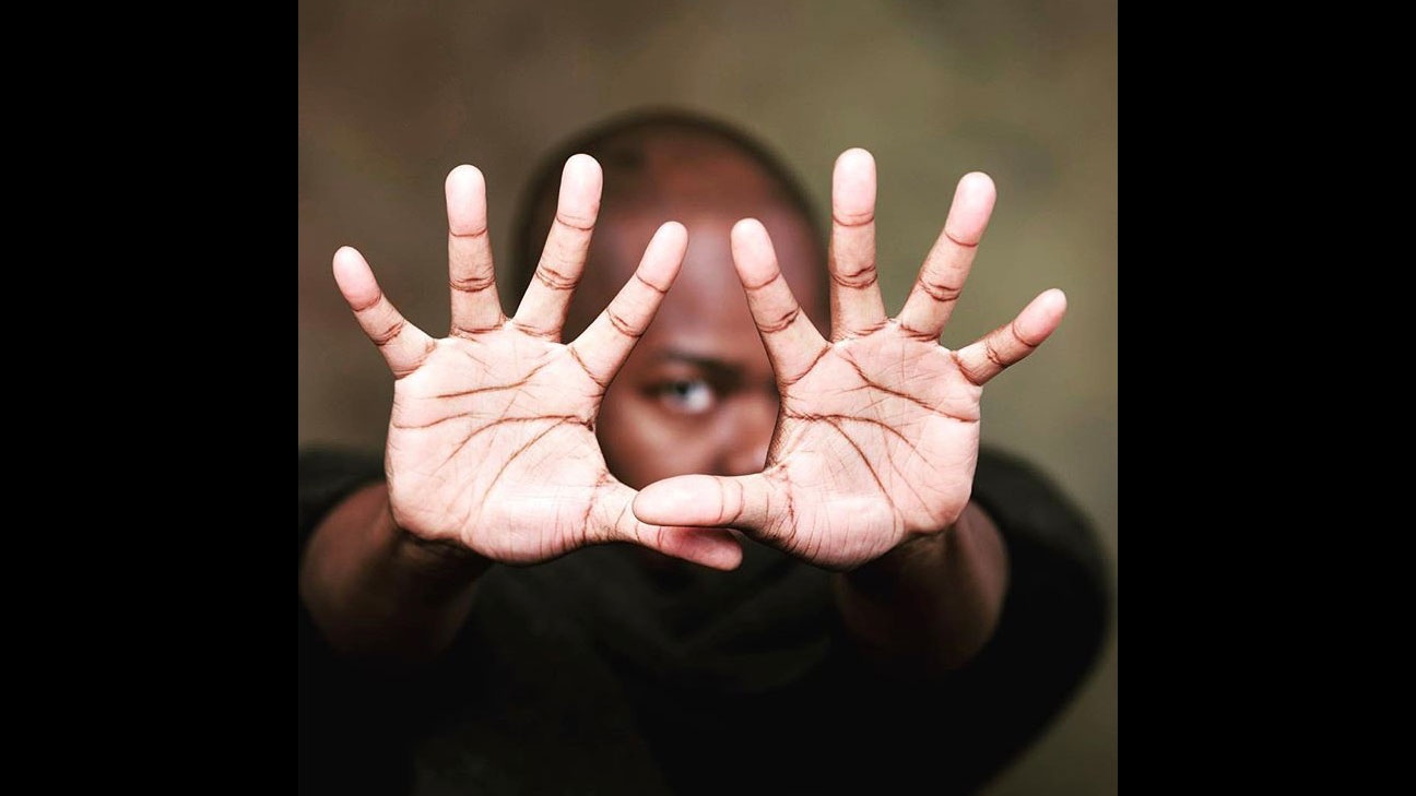 Jaamil Olawale Kosoko with hands out reached to the camera framing his eye. 