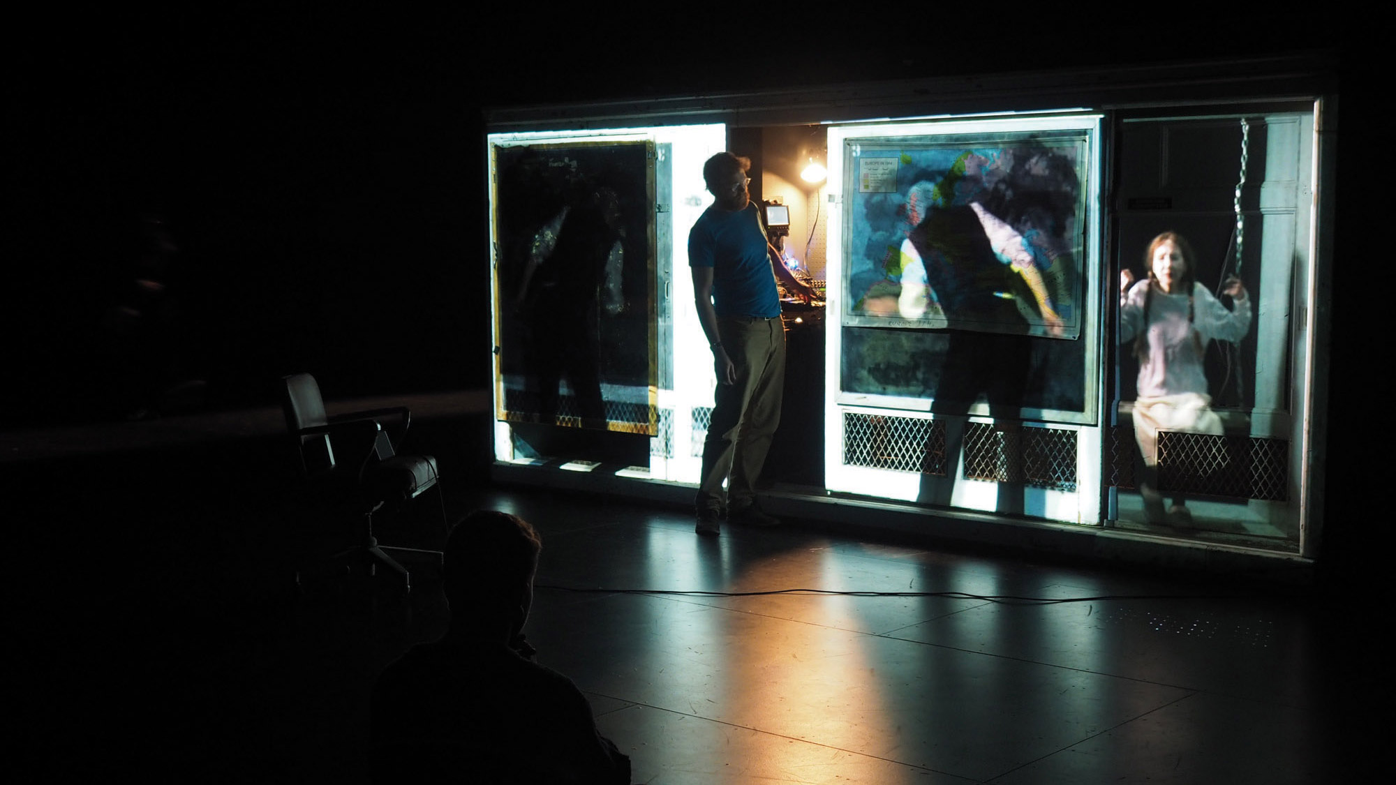 A contemporary man with a beard looking at a projection of a victorian era man and young girl projected over panes of glass. 