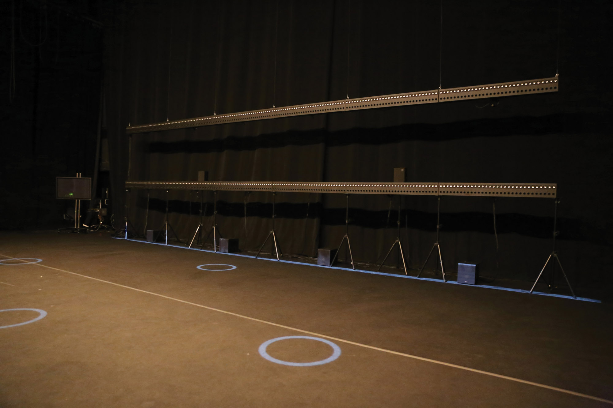 wave field synthesis in a black box studio with project blue rings of light on a black floor. 