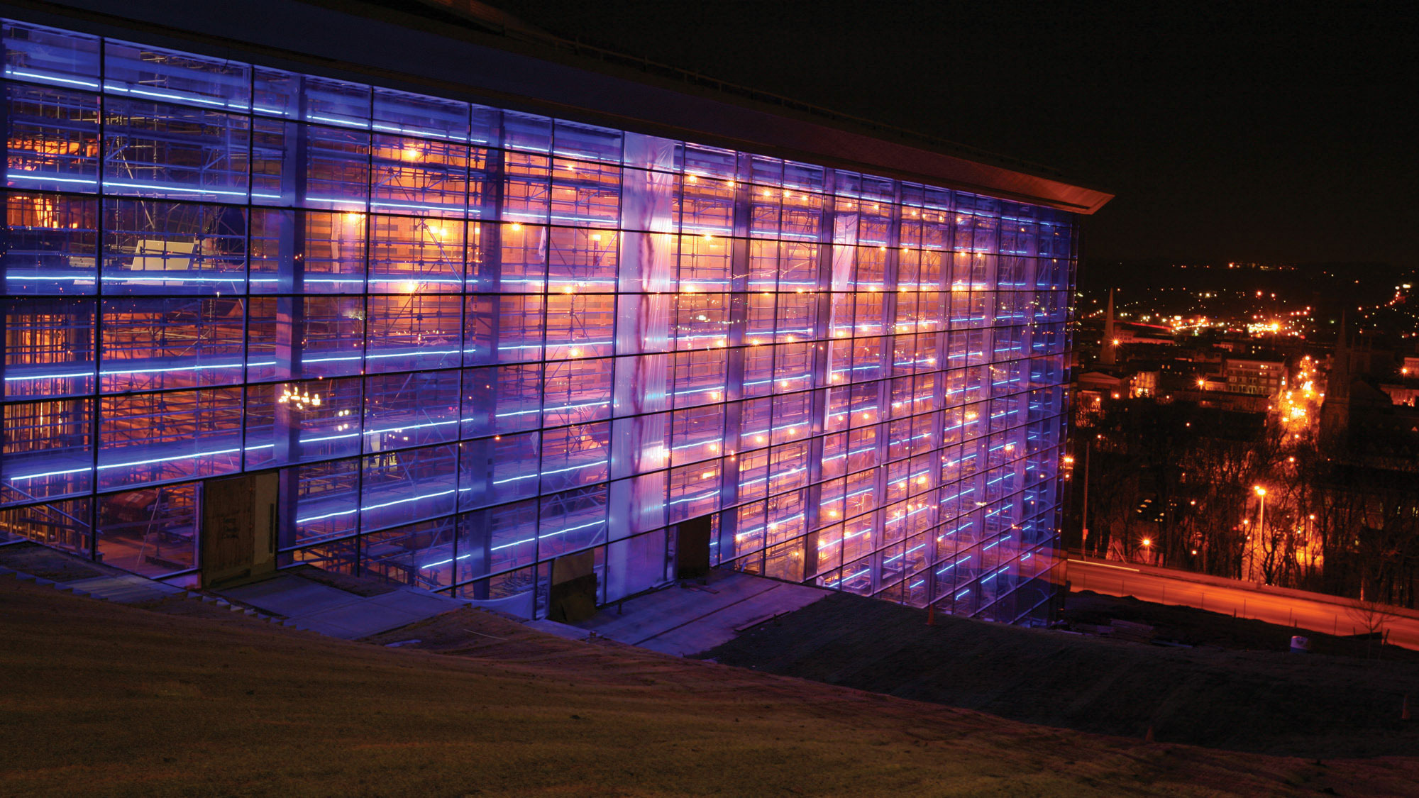The exterior of EMPAC during construction at night lit from within with red light.  