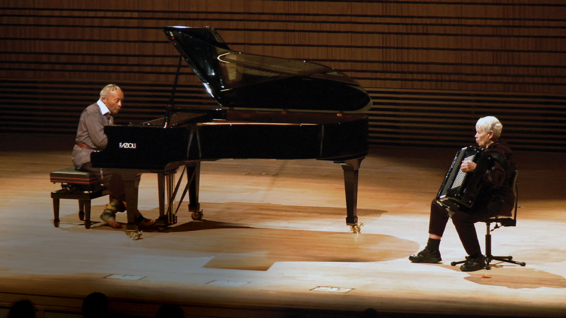 cecil Taylor playing piano and pauline oliveros playing accordion on the concert hall stage. 