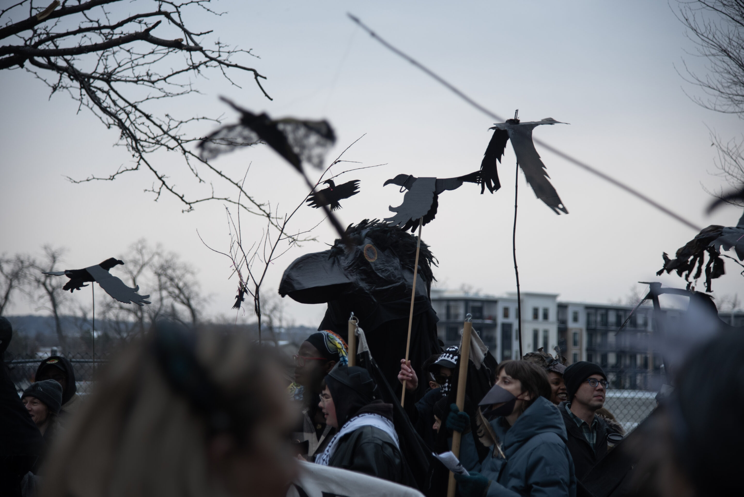 people during the annual crows parade holding crows on sticks and a big paper crow in the center in troy, ny
