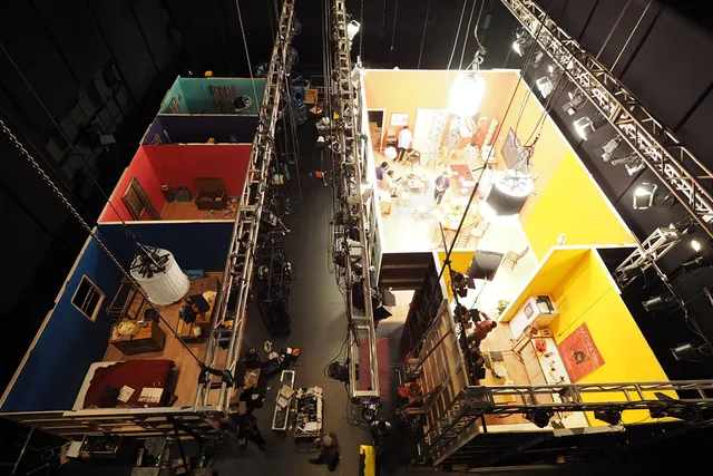An aerial view of an entire film set of colorful rooms built in black box theater. 
