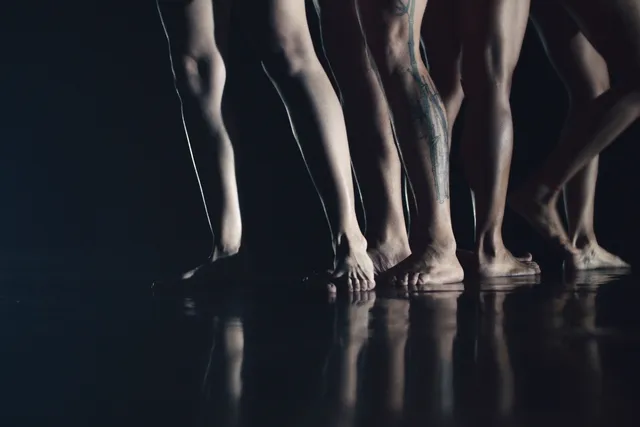 four pairs of legs on a black stage. 