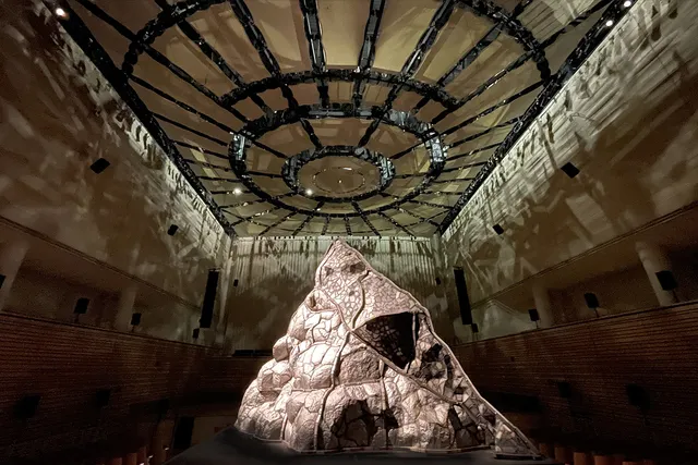 a steel volcano sits in the middle of the concert hall on a platform