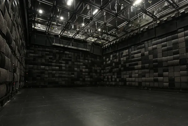a black studio box with black acoustic tiles and a grid