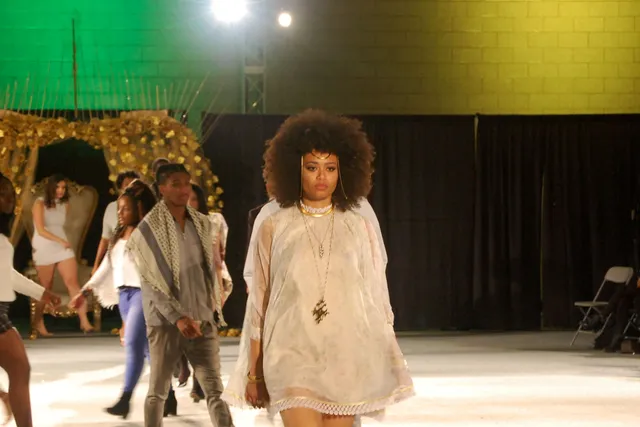 a black woman walks the runway in a white ensemble