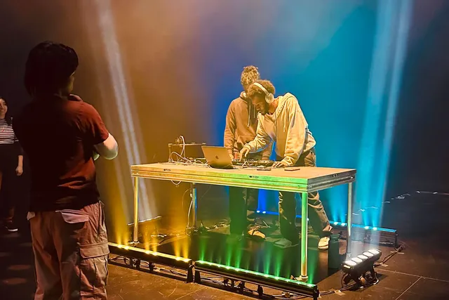 students dj-ing in a black studio with colorful lights on a stainless steel table