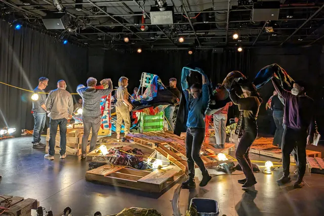 a group of people making a sculpture from pallets in a black box studio
