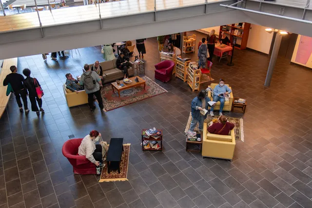 couches and chairs in a cafe with a popup book store in the background. people sitting, conversing, and browsing books.