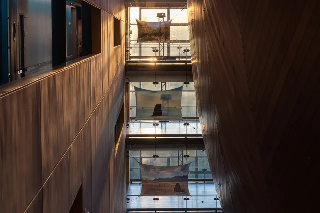 three pieces of material with projections on them across three levels of a building with glass walls of light shining through