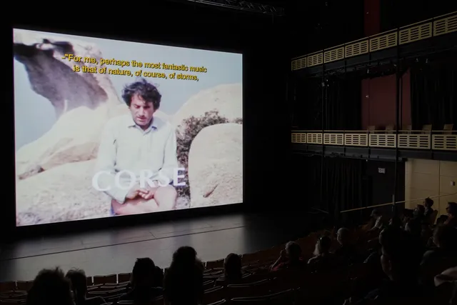 a theater full of people watching a film. 