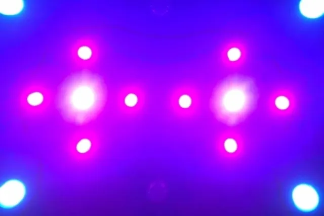 Pink stage lights in a cross formation shine through purple haze. 