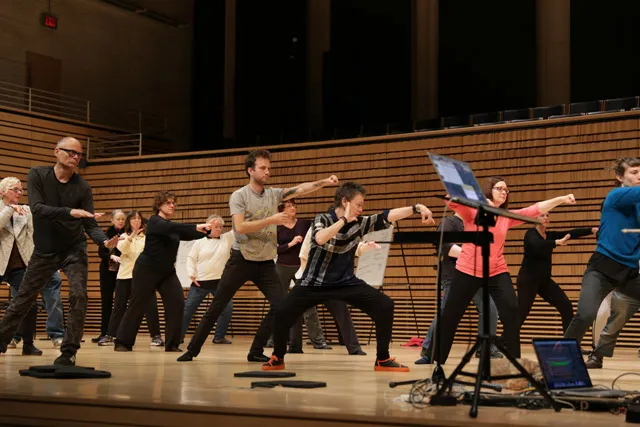 A group of people practicing tai chi with laurie anderson on EMPAC's concert hall stage. 