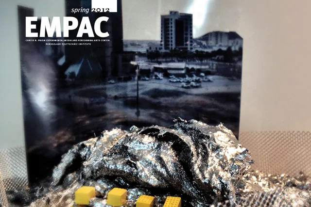 An abstract tinfoil blob in front of a black and white picture of a small cityscape, EMPAC Spring 2012 