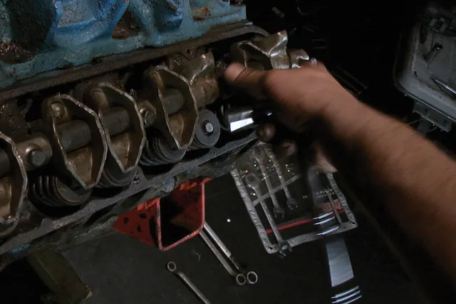 A black hand blurred in motion repairing the cylinder head of an engine. 
