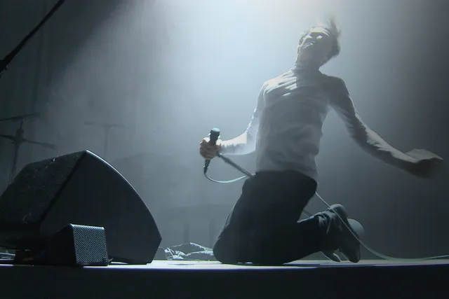 frances starlite holding a microhpone sliding on his knees to the end of the stage in light theatrical fog. 