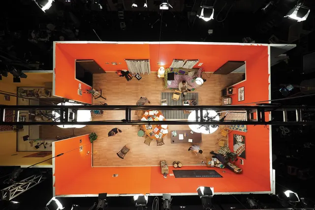 An aerial shot of an orange apartment film set, set up on a black box studio. 