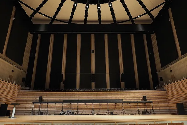 A long rectangular object on multiple supports alone on the concert hall stage. 