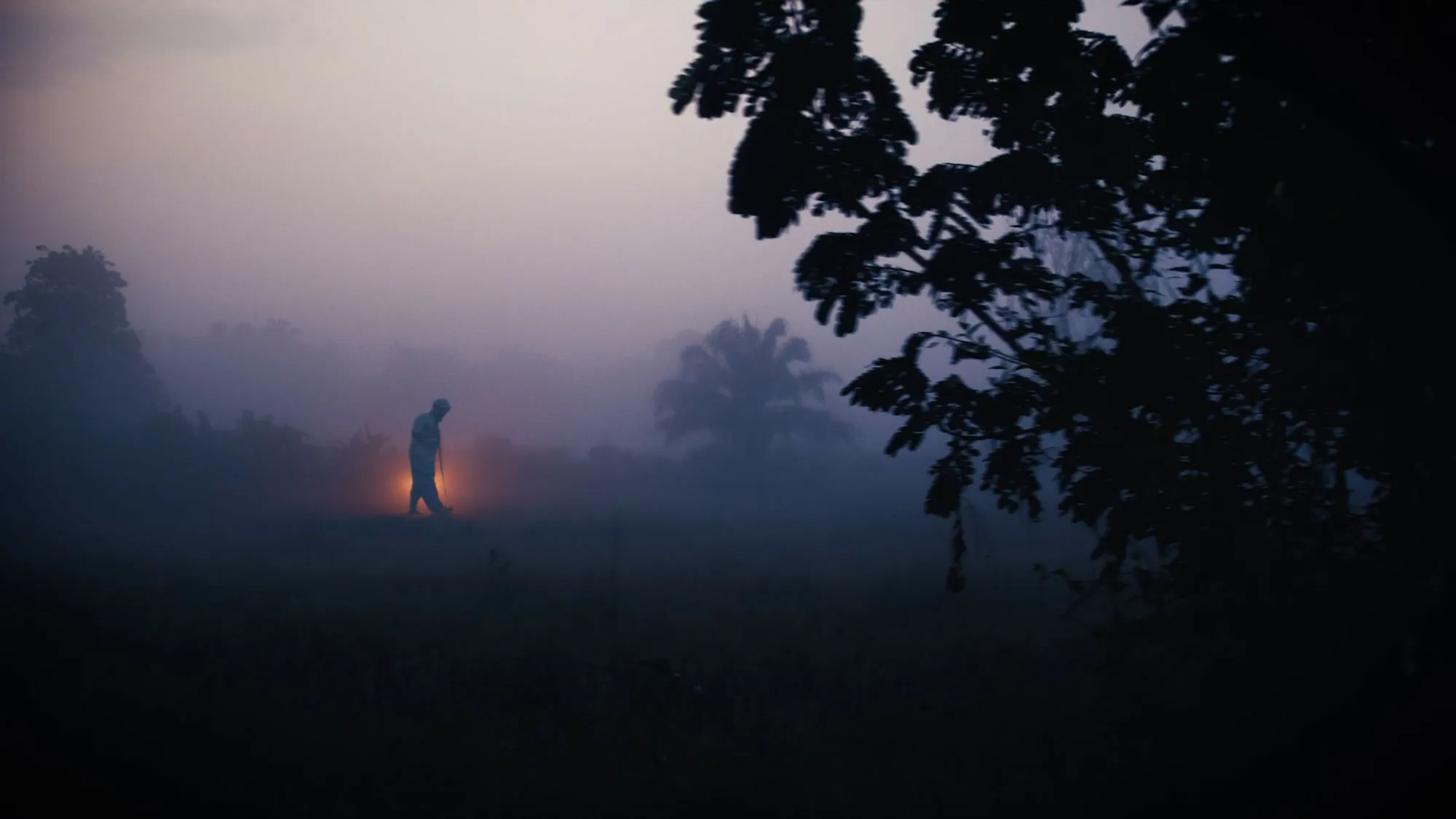 a person in a full white hazmat suit walking in a lush field