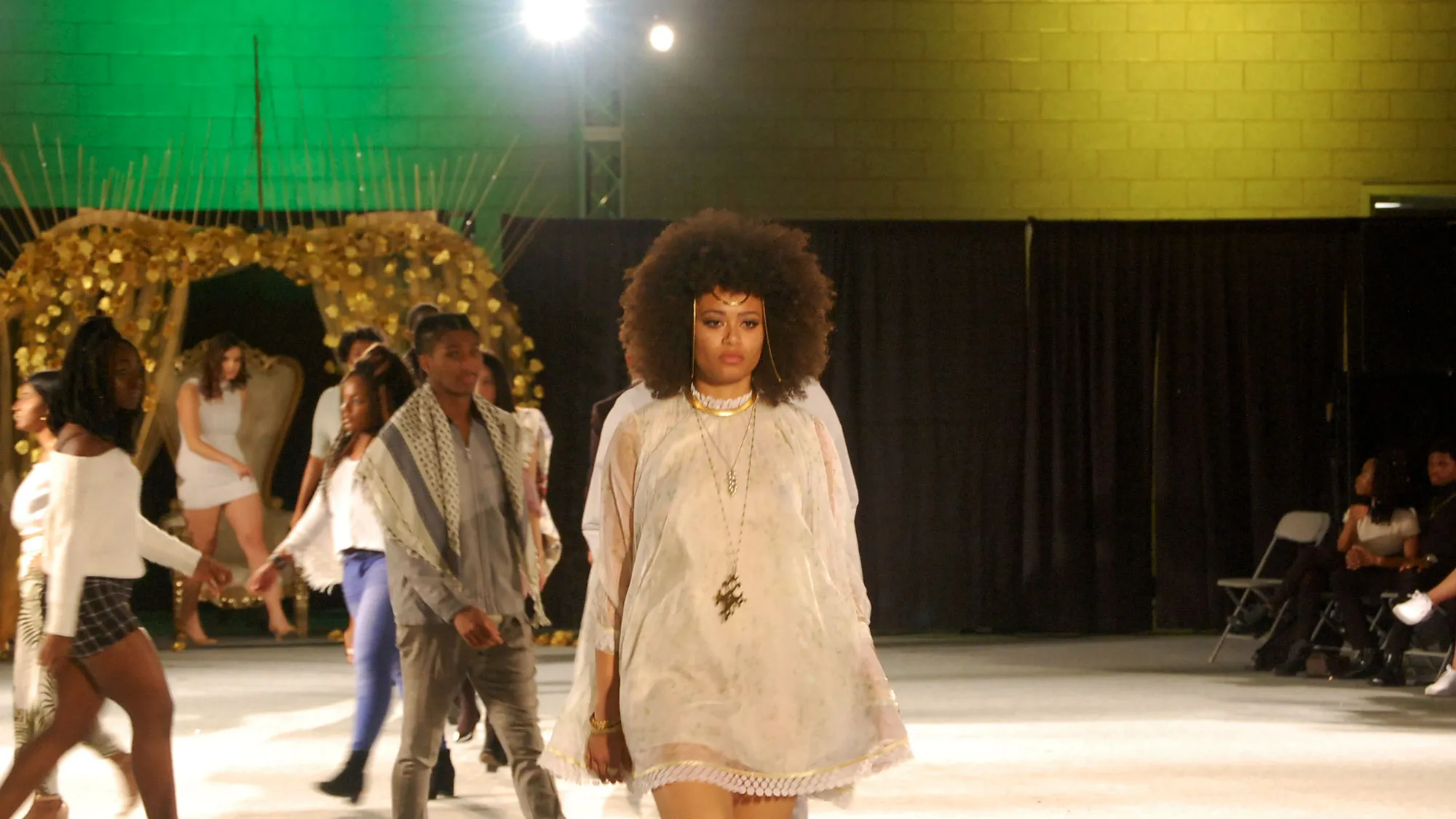 a black woman walks the runway in a white ensemble