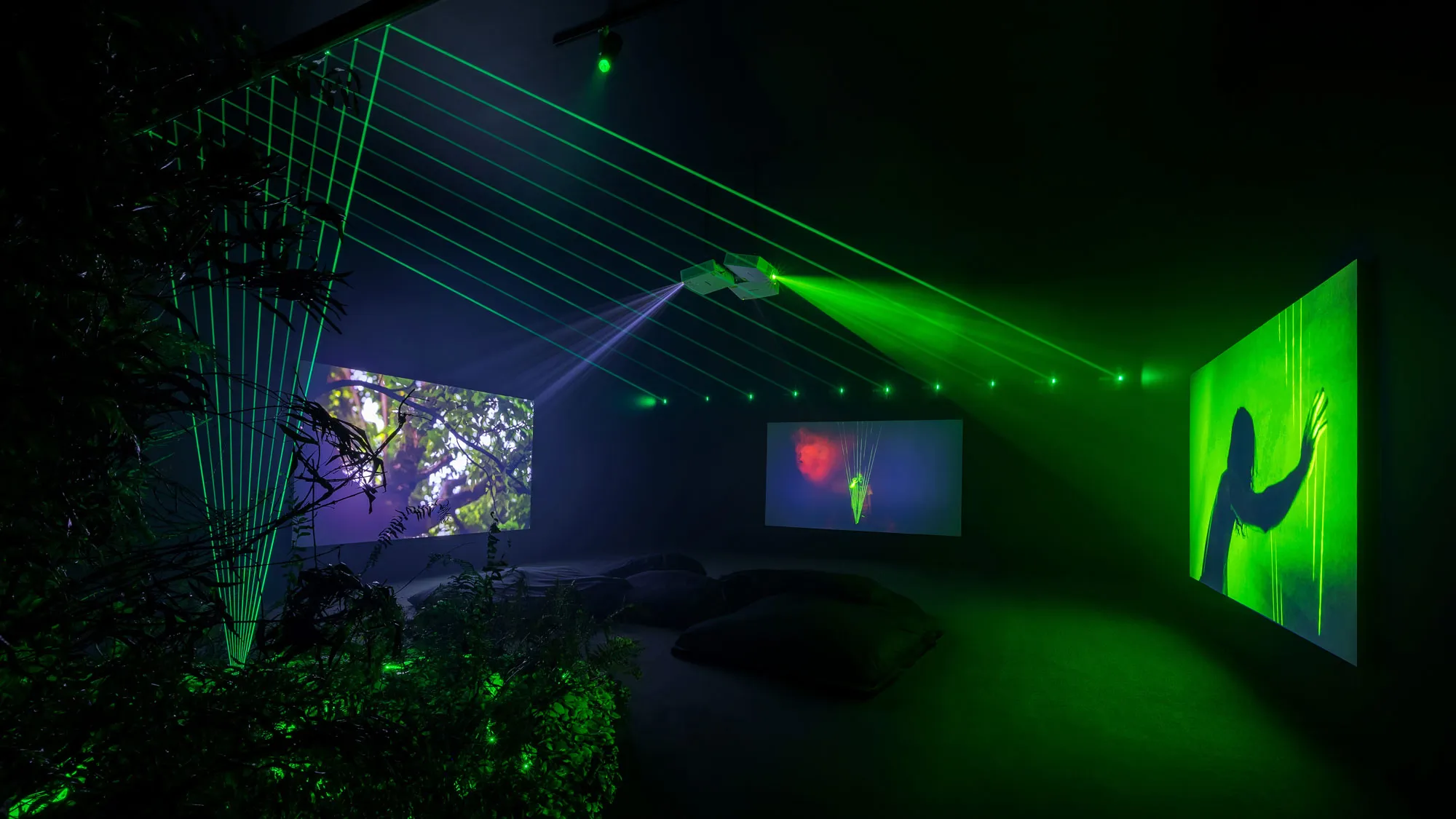 three screens projected on from a central location in a gallery.