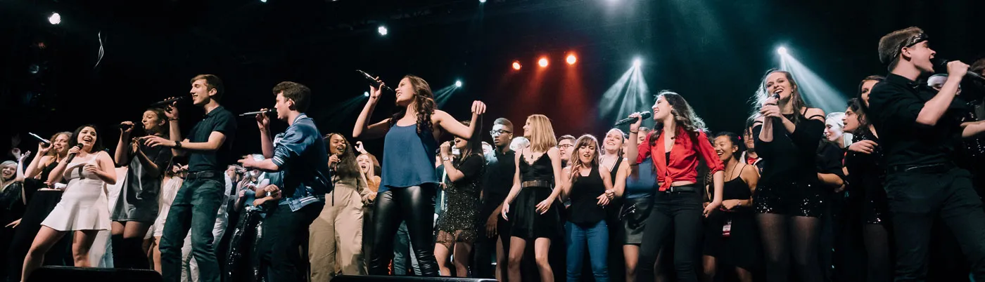a group of young people singing on stage