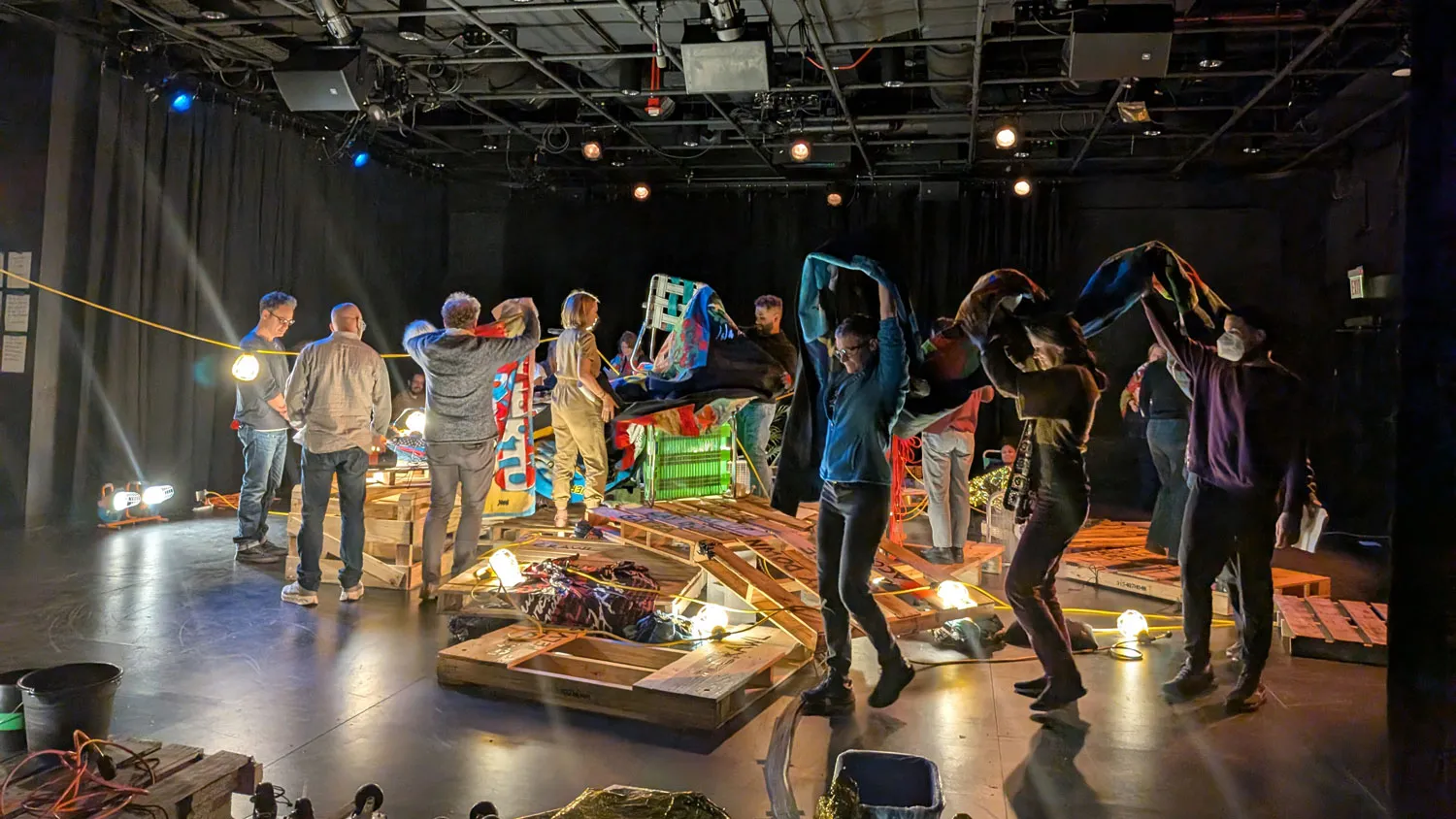 a group of people making a sculpture from pallets in a black box studio