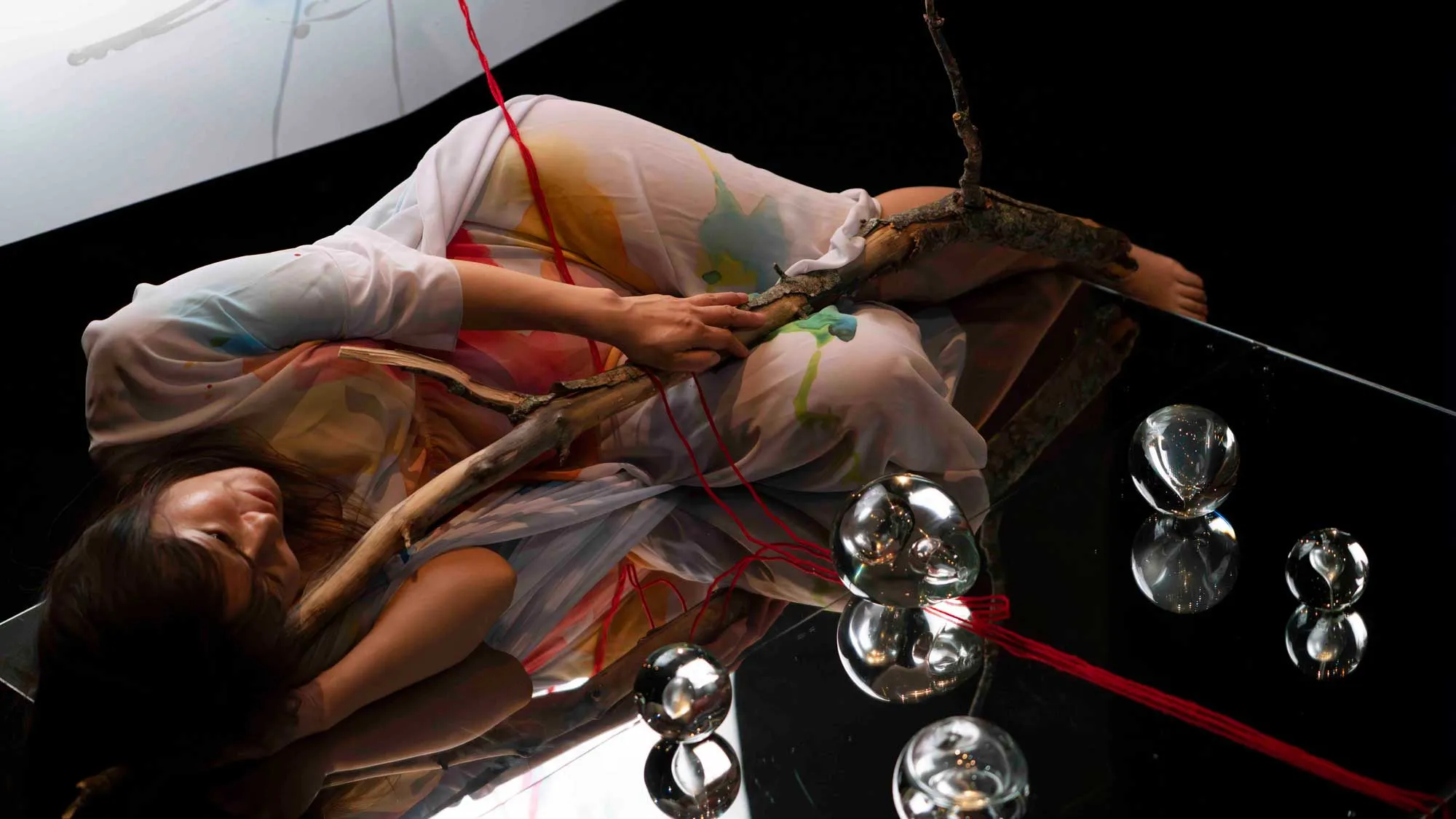 an asian person lying with a twig in a translucent robe