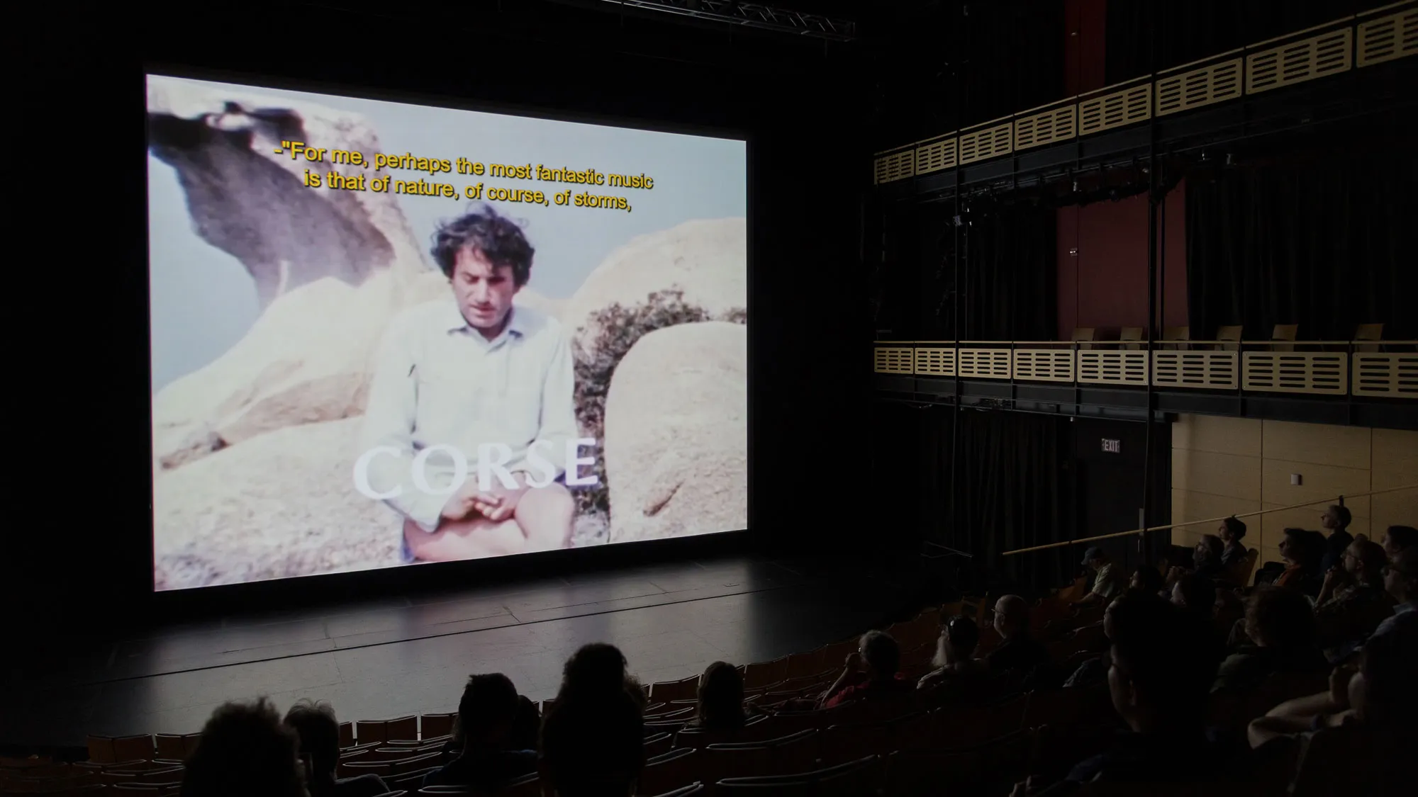 a theater full of people watching a film. 