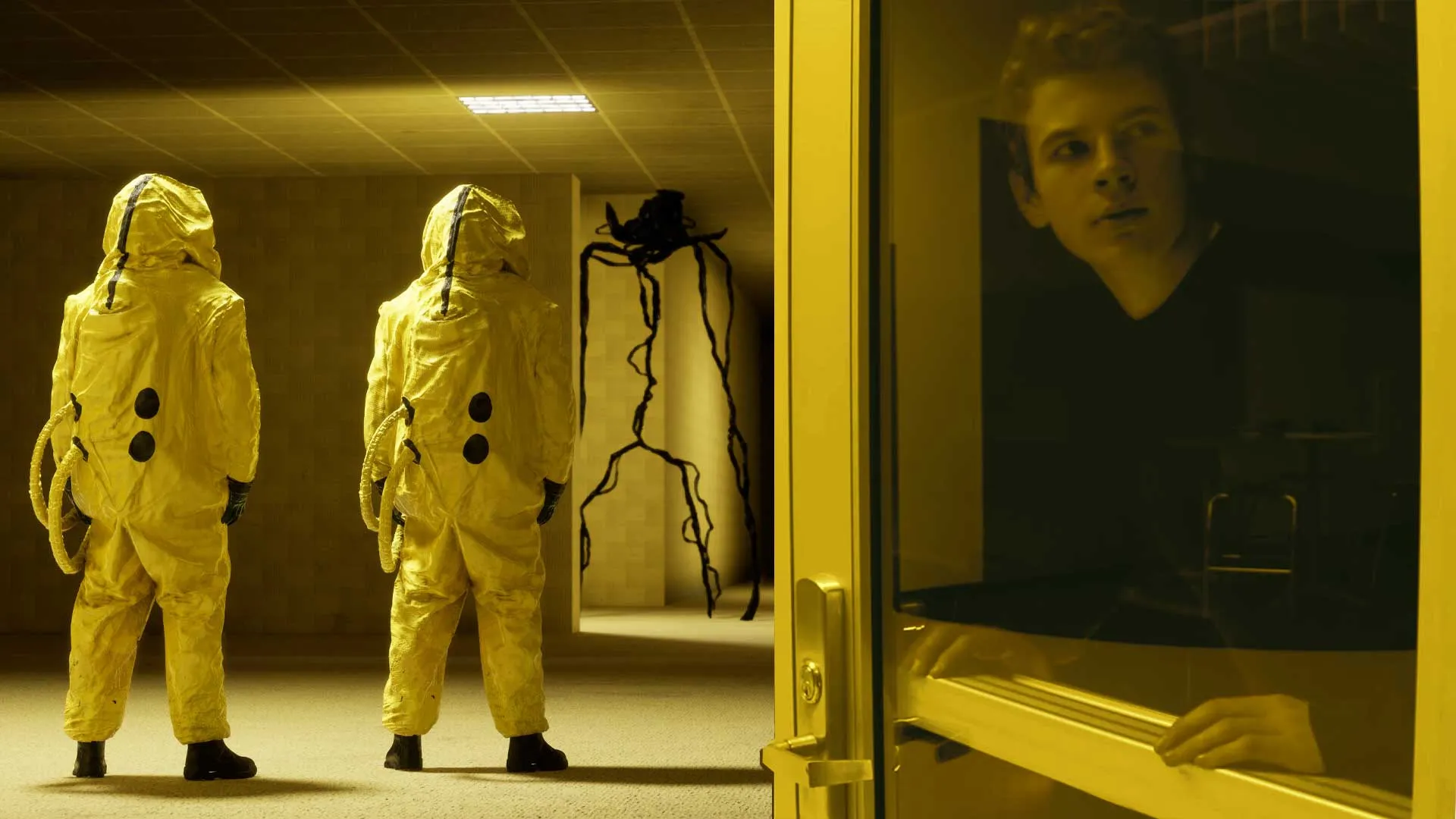 two people in space suits looking down the hall at a spider-like creature