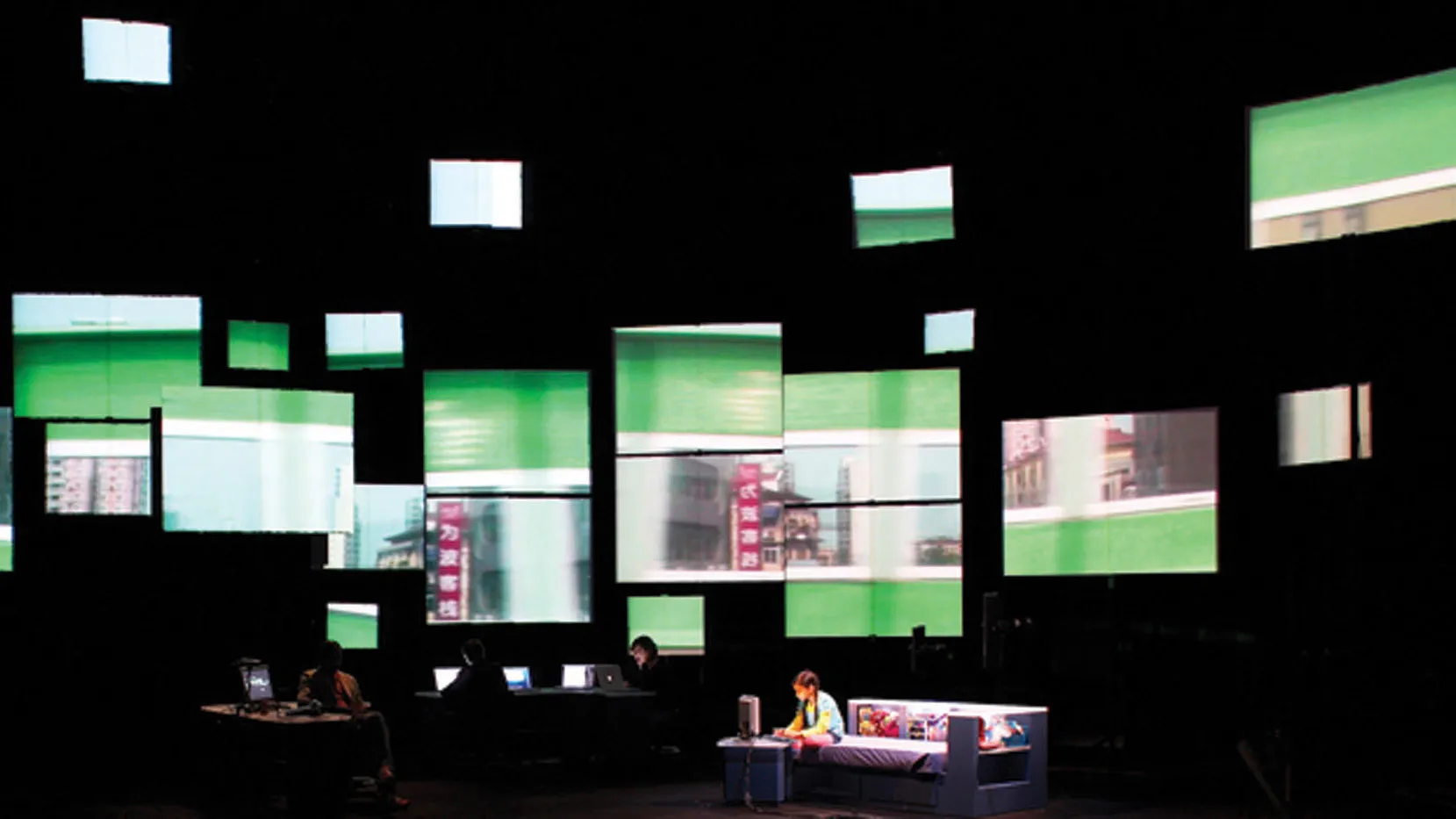 Multiple screens floating on a black wall. A little girl sitting on a bed playing the computer is in the foreground.